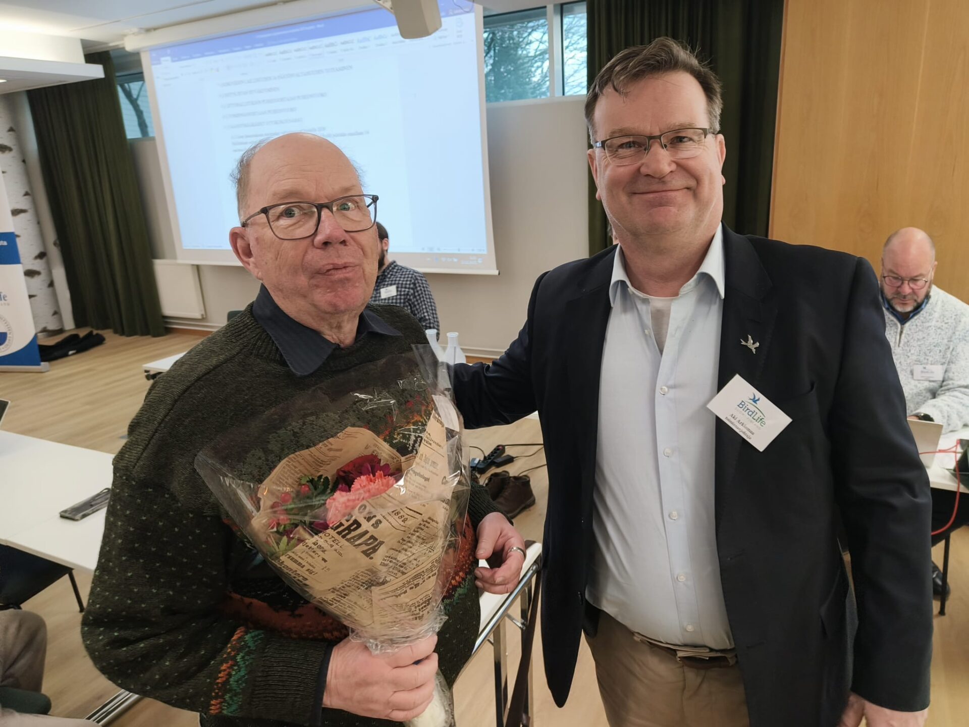 BirdLifen toiminnanjohtaja Aki Arkiomaa onnittelee kunniapuheenjohtaja Pertti Uusivuorta. Kuva: Jyrki Mäkelä